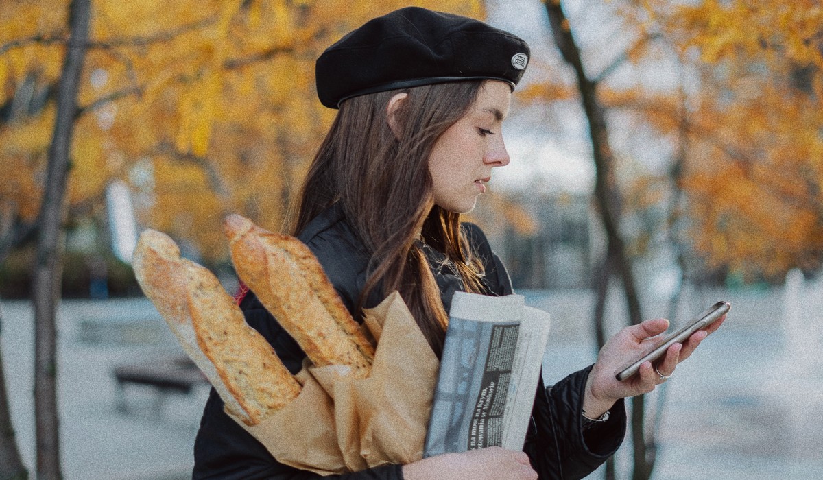 Femme en béret portant des baguettes de pain. ©Unsplash