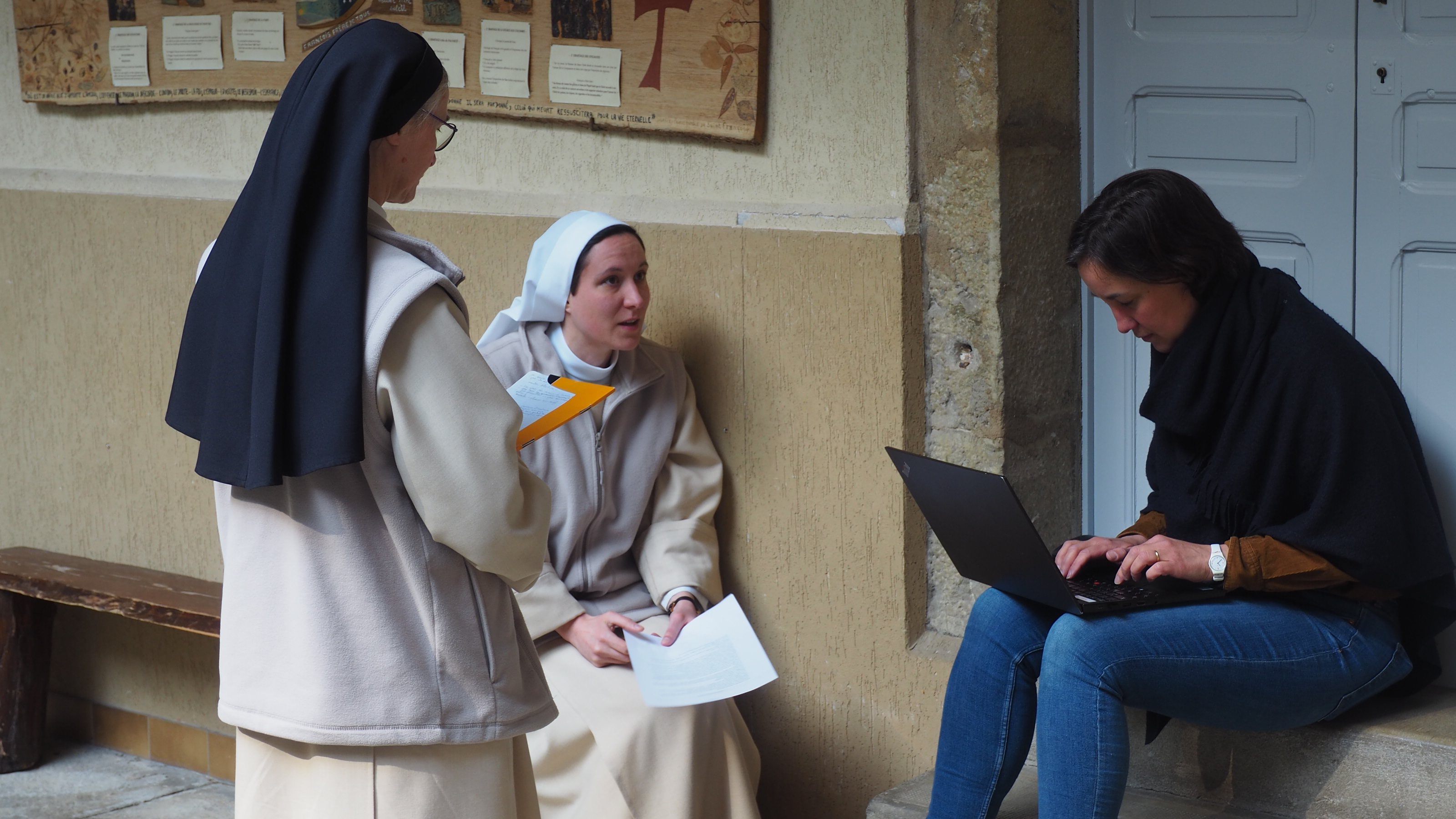 Soeur Pierre Elisabeth assise sur les marches du monastère en discussion avec une autre soeur et la journaliste de RCF Madeleine Vatel / Amélie Gazeau