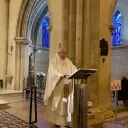 Titre Messe sur fond rose de rubrique Vie spirituelle accompagné du titre lieu à l'espace Bernadette avec sur la droite de la vignette une croix chrétienne blanche et au pied un ensemble d'objets utiles à la communion durant les célébrations eucharistiques