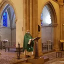 Titre Messe sur fond rose de rubrique Vie spirituelle accompagné du titre lieu à l'espace Bernadette avec sur la droite de la vignette une croix chrétienne blanche et au pied un ensemble d'objets utiles à la communion durant les célébrations eucharistiques