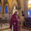 Titre Messe sur fond rose de rubrique Vie spirituelle accompagné du titre lieu à l'espace Bernadette avec sur la droite de la vignette une croix chrétienne blanche et au pied un ensemble d'objets utiles à la communion durant les célébrations eucharistiques