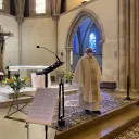 Titre Messe sur fond rose de rubrique Vie spirituelle accompagné du titre lieu à l'espace Bernadette avec sur la droite de la vignette une croix chrétienne blanche et au pied un ensemble d'objets utiles à la communion durant les célébrations eucharistiques