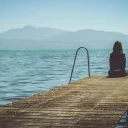 Femme réfléchissant seule sur un ponton ©Photo by Paola Chaaya on Unsplash