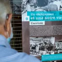 Ancien combattant qui regarde l'exposition "Parcours de Harkis et de leurs Familles"