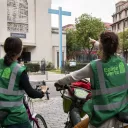 Deux jeunes femmes portant des chasubles au logo "Église verte" à vélo devant la paroisse Saint-Gabriel, Paris, le 16 septembre 2022 ©Corinne Simon / Hans Lucas
