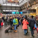 Des voyageurs attendent avec leur bagage et leur valise dans le hall de la gare SNCF Paris Gare de l Est devant des ecrans d information pour les horaires des trains. © Photographie de Nicolas Guyonnet / Hans Lucas