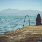 Femme réfléchissant seule sur un ponton ©Photo by Paola Chaaya on Unsplash