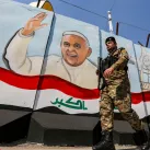 Un membre des forces irakiennes à Bagdad patrouillant le 1er mars 2021 devant un mur peint à l'effigie du pape François  /Crédit : Sabah ARAR / AFP