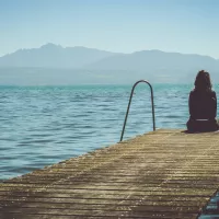 Femme réfléchissant seule sur un ponton ©Photo by Paola Chaaya on Unsplash