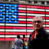 DR - Serge July devant un drapeau américain
