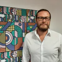 Jérôme Tréhorel, directeur des Vieilles Charrues, devant l'affiche du festival qui fêtera sa 30ème édition. ©Julie Rolland