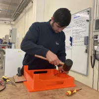 Pasha, en deuxième année à l'école de production, peaufine un réhausse-assiette. © RCF Sud Bretagne