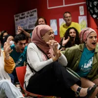 Des membres de l'association pro-burkini "Alliance Citoyenne" regardent le conseil municipal sur un écran de télévision et font la fête lorsque les membres du conseil municipal votent pour autoriser le port du burkini dans les piscines de la ville, à Grenoble le 16 mai 2022. JEFF PACHOUD / AFP