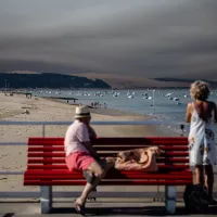 Deux vacanciers observent les fumées du feu de Saint-Magne en Gironde, depuis les plages du Pyla, le 10/08/2022 ©Sophie Garcia / Hans Lucas