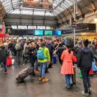 Des voyageurs attendent avec leur bagage et leur valise dans le hall de la gare SNCF Paris Gare de l Est devant des ecrans d information pour les horaires des trains. © Photographie de Nicolas Guyonnet / Hans Lucas