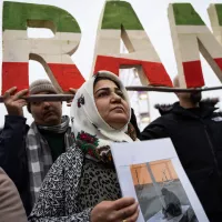 © Nicolas Liponne / Hans Lucas. Lyon, France, 2023-01-08. Une femme porte une pancarte avec une photo devant un logo où il est écrit IRAN lors de la manifestation en soutien au peuple iranien.