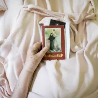 Une femme tient un livre de prière dans son lit de la maison médicale Jeanne-Garnier, centre de soins palliatifs parisien. ©Corinne Simon / Hans Lucas