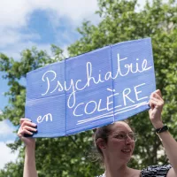 Une femme brandit une pancarte disant Psychiatrie en Colère lors d’une manifestation devant le ministère de la santé en 2022 © Daniel Derajinski / Hans Lucas