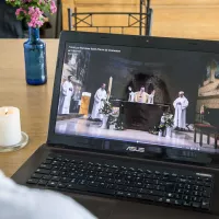 En raison des mesures de confinement, une jeune fille ne peut sortir de chez elle pour assister à la messe de Pâques et la suit en direct sur internet, le 12/04/2020 ©Corinne Simon / Hans Lucas