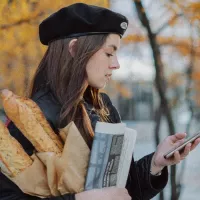 Femme en béret portant des baguettes de pain. ©Unsplash