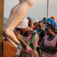 Dans l'Évangile de Matthieu, il y a quelques chose dans la supplication de la Cananéenne qui touche Jésus (Photo : une femme vénère le Christ en Croix, lors du pèlerinage de Ngu Komba, Centrafrique, le 05/12/2019 ©Jean-Matthieu Gautier / Hans Lucas)