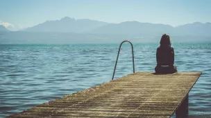 Femme réfléchissant seule sur un ponton ©Photo by Paola Chaaya on Unsplash