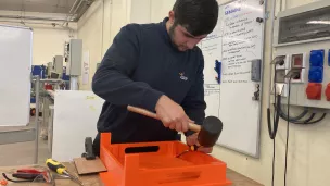 Pasha, en deuxième année à l'école de production, peaufine un réhausse-assiette. © RCF Sud Bretagne