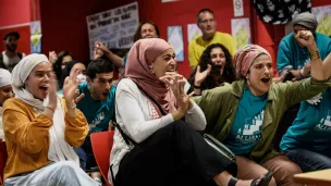 Des membres de l'association pro-burkini "Alliance Citoyenne" regardent le conseil municipal sur un écran de télévision et font la fête lorsque les membres du conseil municipal votent pour autoriser le port du burkini dans les piscines de la ville, à Grenoble le 16 mai 2022. JEFF PACHOUD / AFP