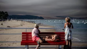 Deux vacanciers observent les fumées du feu de Saint-Magne en Gironde, depuis les plages du Pyla, le 10/08/2022 ©Sophie Garcia / Hans Lucas