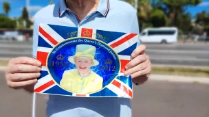 Un niçois tient le drapeau anglais portant la photographie de la reine Elisabeth II sur la Promenade des Anglais à Nice - Photo : RCF Nice Côte d'Azur 