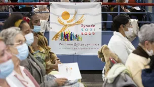 Une banderole sur laquelle est écrit “Synode 2021-2023” est accrochée dans l'assemblée, lors de la célébration de la messe chrismale au Palais des sports de la ville de Créteil. Créteil, 12 avril 2022. © Corinne SIMON / Hans Lucas.