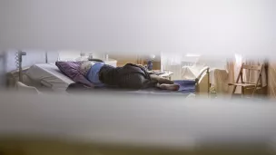 Unite de soins palliatifs a la maison medicale Jeanne Garnier. Patiente allongee sur son lit, vue a travers le hublot ouvert de sa chambre. Paris (75), 6 juin 2018. Photographie de Corinne SIMON / Hans Lucas. 