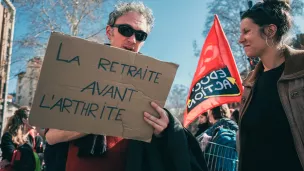 Manifestant à Toulouse avec pancarte “La retraite avant l’arthrite” © Patrick Batard / Hans Lucas