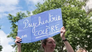 Une femme brandit une pancarte disant Psychiatrie en Colère lors d’une manifestation devant le ministère de la santé en 2022 © Daniel Derajinski / Hans Lucas