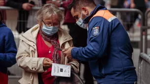 Agent de protection civile vérifiant le passe vaccinal d'individus. ©Unsplash