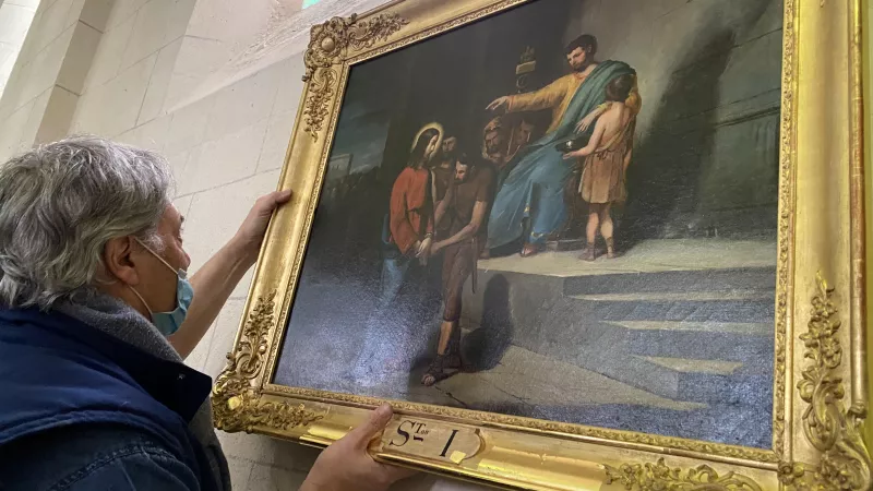 Le restaurateur Patrick Buti accroche les toiles au mur de l'église de Saint-Germain-des-Prés