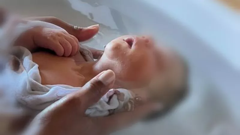 Un bébé apaisée par un bain thérapeutique emmailloté