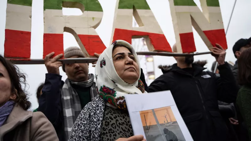© Nicolas Liponne / Hans Lucas. Lyon, France, 2023-01-08. Une femme porte une pancarte avec une photo devant un logo où il est écrit IRAN lors de la manifestation en soutien au peuple iranien.