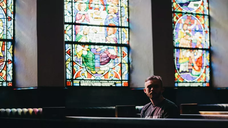 Homme assis dans une église. ©Unsplash