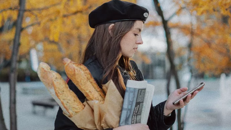 Femme en béret portant des baguettes de pain. ©Unsplash
