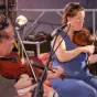 Titre de Galaxie musique sur fond orange de rubrique Culture avec en illustration centré et droite une vielle marron sur un ensemble de flûtes traditionnelles épaisses en bois