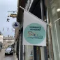 Drapeau de l'association des commerçants "shop'in Alençon" flottant sur la devanture d'un magasin d'habillement.