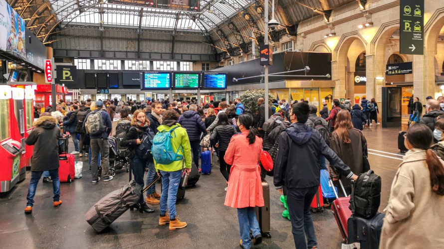 Des voyageurs attendent avec leur bagage et leur valise dans le hall de la gare SNCF Paris Gare de l Est devant des ecrans d information pour les horaires des trains. © Photographie de Nicolas Guyonnet / Hans Lucas