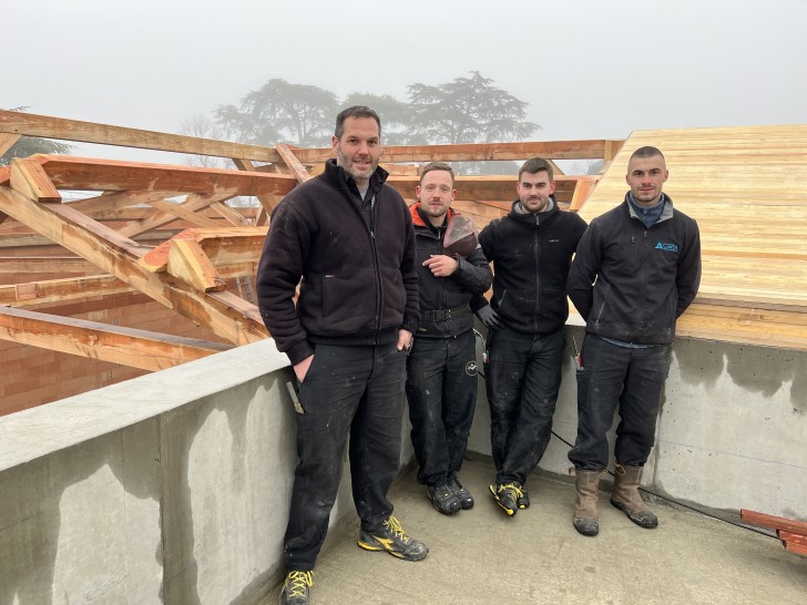 Le charpentier Christophe Morisson et son équipe devant la charpente en construction du futur cuvage