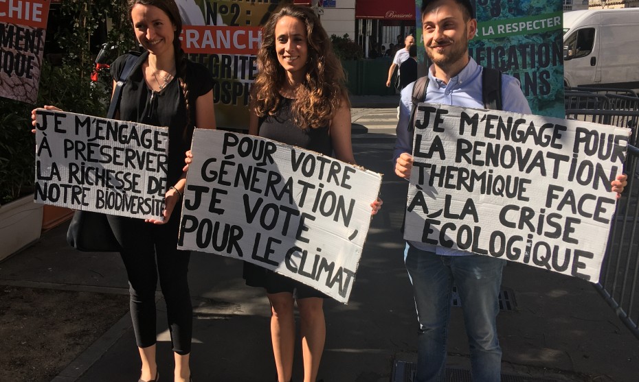 La députée insoumise Clémence Guetté (au centre) pose avec son équipe en tenant des panneaux préparés par les Jeunes pour le climat - © RCF Lyon 2022 (JB Cocagne)